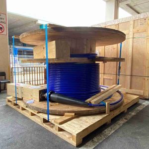 Large blue industrial cable reel prepared for shipment on a wooden pallet.