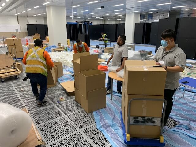 Logistics team packing and preparing boxes for shipment in a data center.